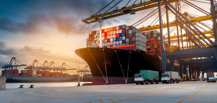 crane loading cargo container from truck to container ship in th