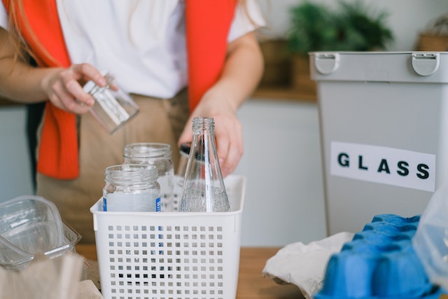 A person sorting trash for recycling as one of the examples of ways to minimize your carbon footprint during a move.