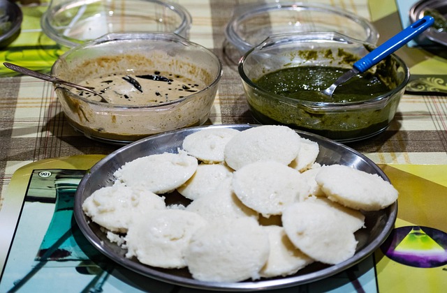 Steamed South Indian idli served with coconut chutney and sambar on plate