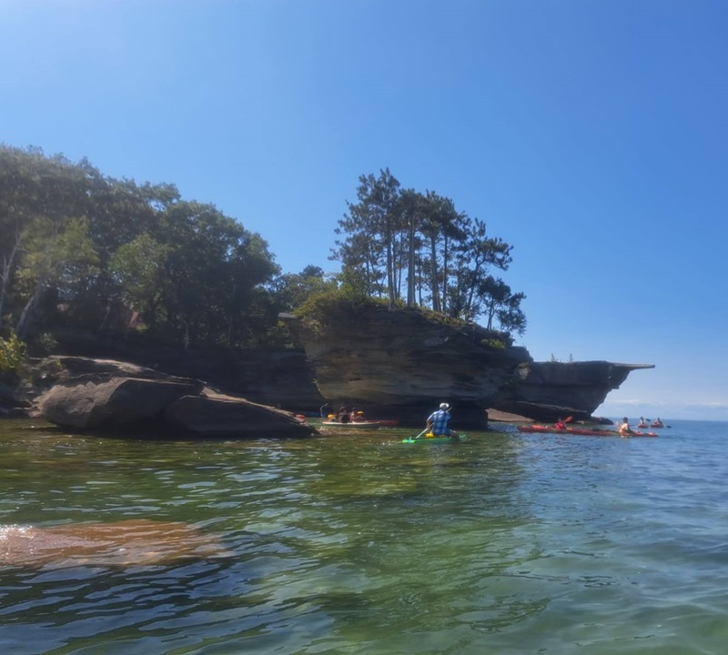 Solo kayaker paddling across the shallow clear waters of Lake Huron near Port Austin on the route to Turnip Rock.