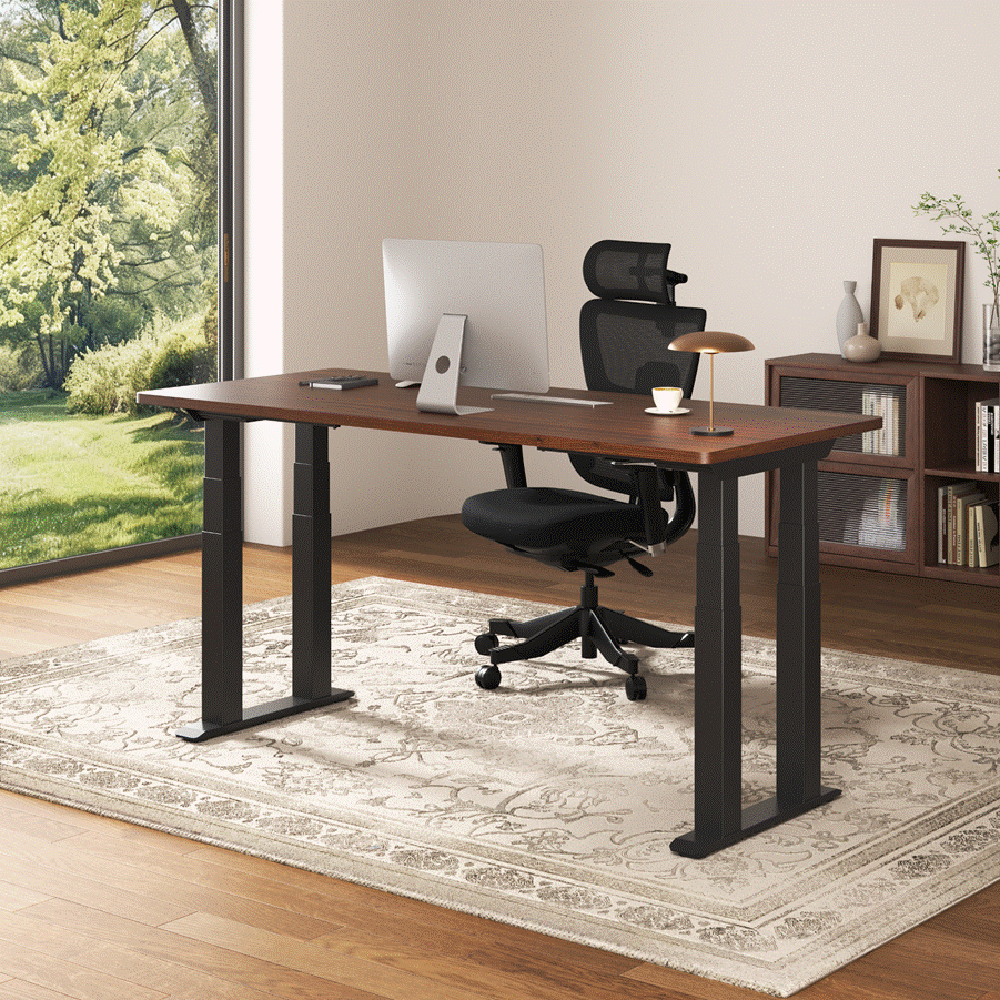 Modern home office with a wood-top standing desk, desktop monitor, black ergonomic chair, lamp, and coffee cup beside a large window overlooking a green yard