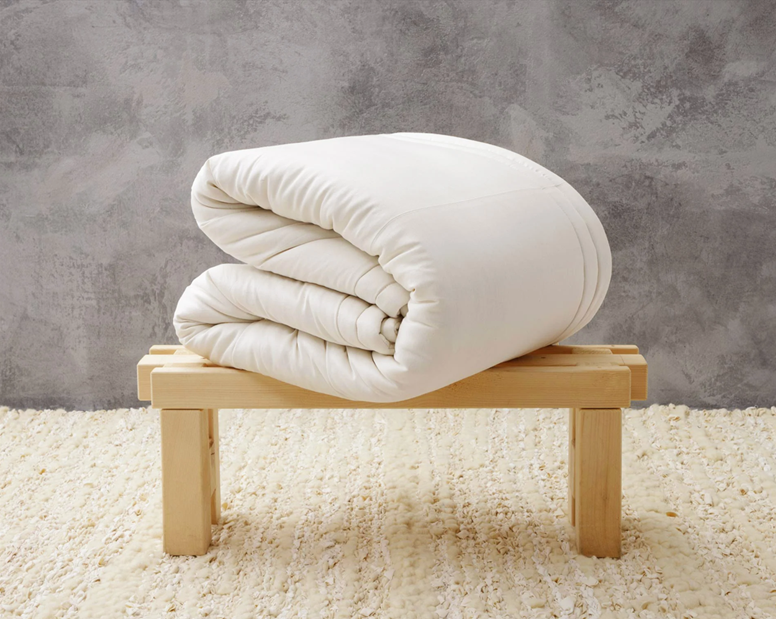 Folded white comforter placed on a small wooden bench